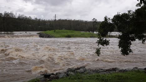 Coomera,-Gold-Coast,-2-January-2024---Wide-shot-of-turbulent-water-across-the-Coomera-River-Causeway-under-flood-waters-from-the-2024-Storms-in-January