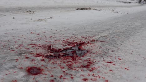 Car-drives-over-patch-of-blood-on-snowy-road,-results-of-car-accident,-60-fps