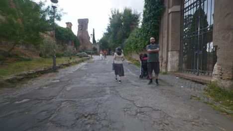 Rome-Immersive-POV:-Moving-In-Busy-Streets-to-Chiesa-Santi-Luca-e-Martina,-Italy,-Europe,-Walking,-Shaky,-4K-|-Family-Near-Ruins-Gate