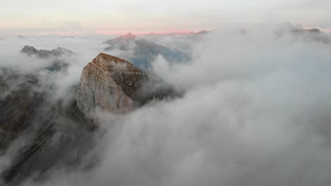 Aerial-timelapse-view-of-Tour-de-Mayen-in-Leysin,-Vaud,-Switzerland-with-clouds-flowing-past-the-mountain-peaks-and-cliffs-on-a-colorful-autumn-afternoon-in-the-Swiss-Alps