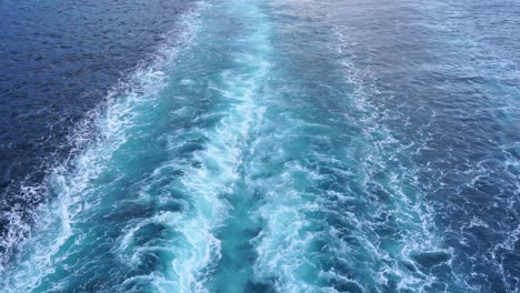 Blue-stern-waves-on-the-ocean,-beautiful-pattern-on-the-foamy-water-surface