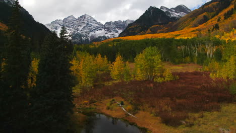 Colorful-Colorado-cinematic-aerial-drone-Aspen-Maroon-Bells-Capital-Peak-wilderness-14ers-autumn-fall-Aspen-Trees-first-snow-cloudy-morning-dramatic-incredible-landscape-forward-pan-up-reveal-motion