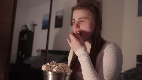 Young-woman-engrossed-in-humorous-movie-and-delicious-bucket-of-popcorn
