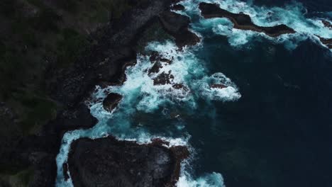 Aerial-dolly-shot,-rocky-coastline-invaded-by-ocean-wave-crash
