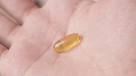 Hand-showing-an-omega-3-fish-oil-capsule-to-the-camera
