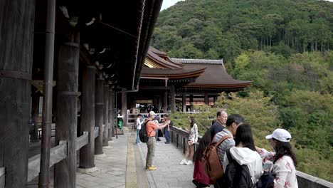 Visitors-at-the-promenade-of-Kiyomizudera-Temple-in-Kyoto,-Japan,-delight-in-the-panoramic-view-of-the-natural-surroundings-and-architectural-marvel
