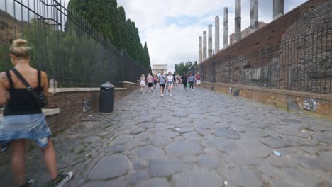 Punto-De-Vista-Inmersivo-En-Roma:-Moverse-Por-Calles-Concurridas-Hasta-Chiesa-Santi-Luca-E-Martina,-Italia,-Europa,-Caminar,-Tembloroso,-4k-|-Pareja-En-Multitud-Cerca-De-Ruinas-Antiguas