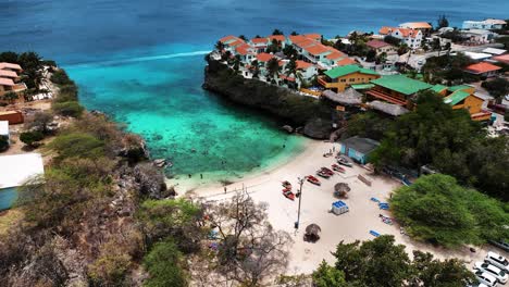 The-drone-is-flying-above-a-small-beach-between-a-village-in-Curacao-Aerial-Footage-4K