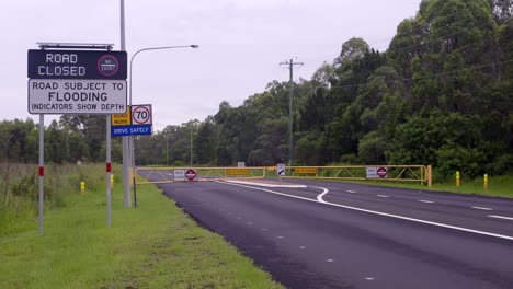 Road-closure-with-flooding-sign-and-flashing-closed-sign-on-Brisbane-Road,-Australia