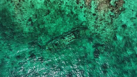 The-drone-is-flying-topdown-looking-at-a-shipwreck-in-the-ocean-going-up-and-rotating-in-Curacao-Aerial-Footage-4K