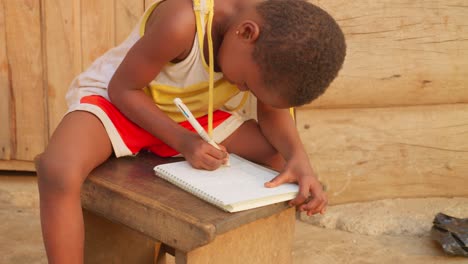 Nahaufnahme-Eines-Jungen-Studenten,-Der-Notizen-Schreibt-Und-Hausaufgaben-Macht,-Während-Er-In-Einer-Schule-In-Einem-Armen,-Abgelegenen-Ländlichen-Dorf-In-Afrika-Studiert