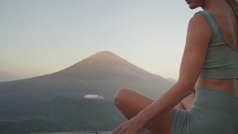 Woman-journaling-thoughts-and-feelings-in-front-of-Mount-Agung,-sunrise