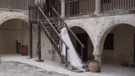 Eine-Braut-Posiert-Für-Fotos-Auf-Den-Stufen-Einer-Griechischen-Kopfsteinpflastervilla