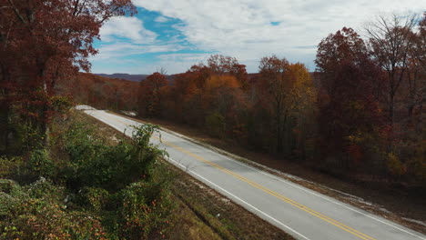 Arkansas-countryside-road-in-Autumn-fall-season,-orange-forest-trees,-tilt-up
