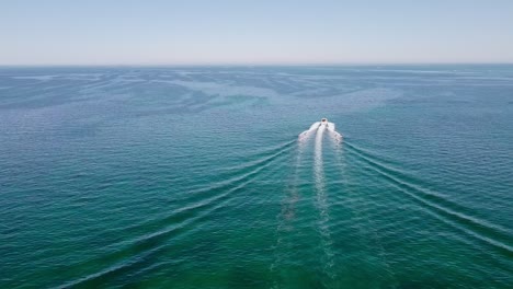 Speedboat-cuts-through-water,-leaving-frothy-trail-as-it-races-towards-horizon