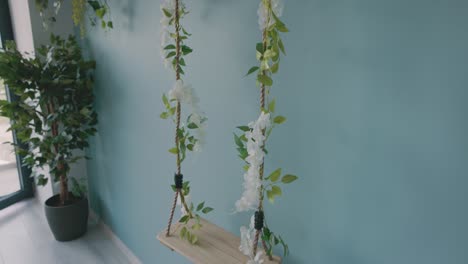 A-Wooden-Swing-Hanging-Against-the-Wall-of-a-Beauty-Salon,-Embellished-with-Artificial-Leaves-and-Flowers