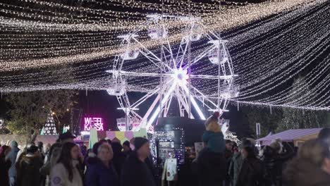 Beleuchtetes-Riesenrad-Und-Weihnachtsbeleuchtung-Im-überfüllten-Vergnügungspark-Bei-Nacht