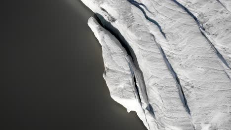 Aerial-flyover-with-an-overhead-view-of-the-ice-and-crevasses-at-the-glacial-lake-next-to-Claridenfirn-glacier-in-Uri,-Swizerland