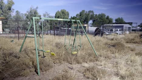 Abandoned-swing-set-in-overgrown-rural-dry-grass