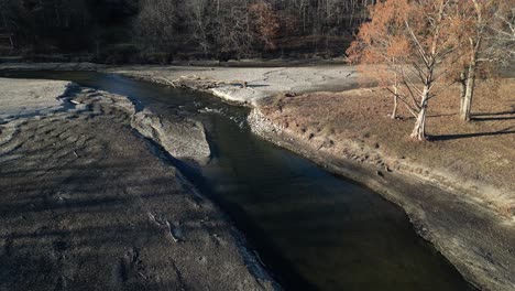 Drone-view-of-a-pond-and-river-flow-that-is-badly-eroded-with-a-fallen-tree