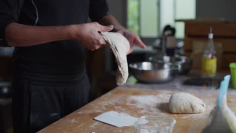 Freshly-risen-dough-pulled-and-stretched-by-hand,-filmed-in-in-medium-closeup-slow-motion-shot