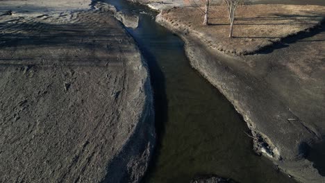 Ein-Stark-Erodierter-Flusslauf-Mit-Trockenem-Baum-Im-Hintergrund
