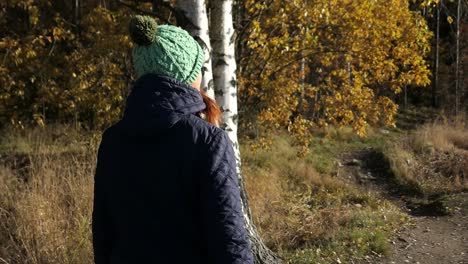 Woman-walking-forest-path-peacefully,-enjoying-nature-in-fall