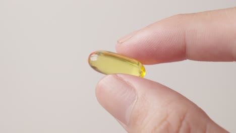 Hand-holding-fish-oil-supplement-yellow-pill