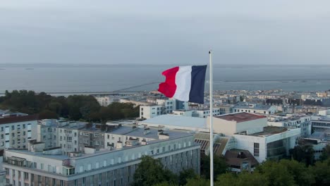 Drone-orbits-French-flag,-unveils-Brest-city-skyline