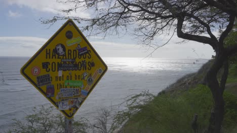 Ein-Schild,-Das-Auf-Gefährliche-Bedingungen-In-Der-Nähe-Einer-Klippe-Am-Diamond-Head-Hawaii-Hinweist,-Ist-Mit-Aufklebern-Bedeckt