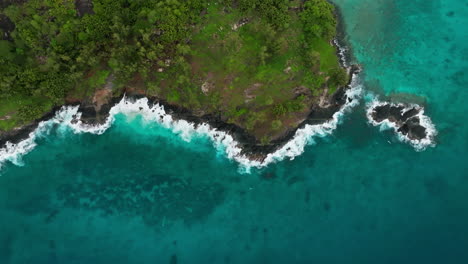 Top-down-aerial-drone-view-waves-crushing-on-rocky-coastline