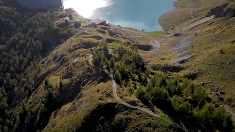 Aerial-view-of-Lac-de-Salanfe-and-its-hydroelectric-dam-in-Valais,-Switzerland-on-a-sunny-autumn-day-in-the-Swiss-Alps-with-a-pan-up-view-to-surrounding-alpine-peaks-and-cliffs