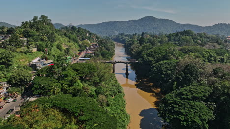 Peradeniya-Sri-Lanka-Aerial-v5-cinematic-drone-fly-along-Mahaweli-Ganga-river,-flyover-A1-main-road-bridge-capturing-suburbs-in-Kandy-and-hillside-landscape-views---Shot-with-Mavic-3-Cine---April-2023
