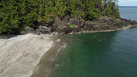 Secret-Cove-Aerial-Drone-Pull-Out-Pedestal-Shot-Over-Coastal-Beach-and-Forest