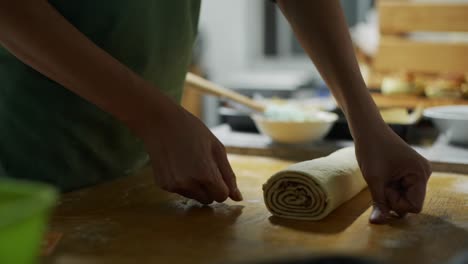 Raw-and-uncooked-cinnamon-roll-dough-measured-and-cut-using-kitchen-thread-on-wooden-table-top,-filmed-as-close-up-slow-motion-shot