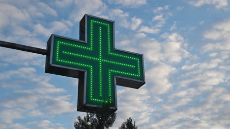Illuminated-green-pharmacy-cross-in-front-of-the-drugstore