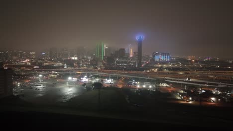 Dallas,-Texas-skyline-at-night-with-foggy-weather-and-drone-video-moving-in-close-up