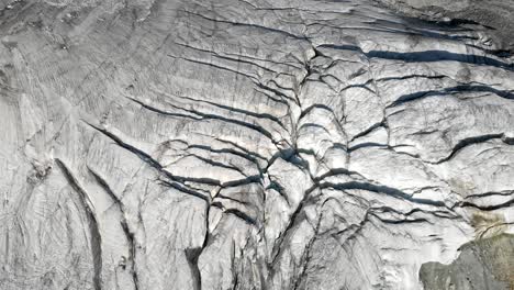 Aerial-flyover-over-a-glacier-near-Arolla-in-Valais,-Switzerland-with-a-spinning-panning-view-from-the-glacier-ice-towards-the-sunlit-Val-d'Herens-valley