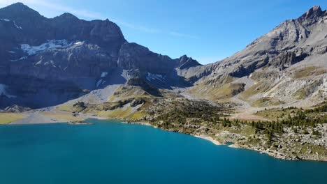 Aerial-flyover-over-the-hydrolectric-dam-and-Lac-de-Salanfe-in-Valais,-Switzerland-on-a-sunny-autumn-day-in-the-Swiss-Alps-with-a-view-of-alpine-peaks-and-cliffs-in-background