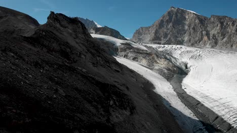 Luftüberflug-Entlang-Einer-Klippe-Neben-Dem-Allalin-Gletscher-Mit-Blick-Auf-Den-Allalinhorn-Gipfel-In-Der-Nähe-Von-Saas-Fee-Im-Wallis,-Schweiz-An-Einem-Sonnigen-Sommertag-In-Den-Schweizer-Alpen