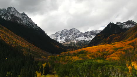 Colorful-Colorado-cinematic-aerial-drone-Aspen-Maroon-Bells-Capital-Peak-wilderness-14ers-autumn-fall-Aspen-Trees-first-snow-cloudy-morning-dramatic-incredible-landscape-downward-motion