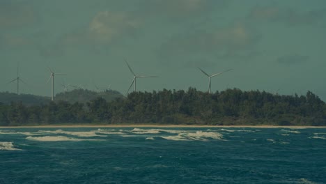 Turbinas-Eólicas-Gigantes-Salpican-La-Línea-Del-Horizonte-Cerca-De-La-Costa-De-Honolulu,-Hawaii,-Proporcionando-Sus-Fuentes-De-Energía-Sostenibles