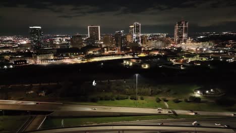Fort-Worth,-Texas-skyline-at-night-with-drone-video-pulling-back-showing-freeway