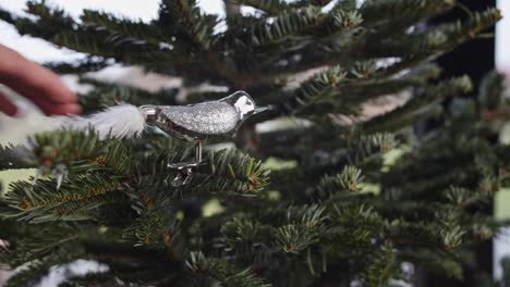 Un-Elegante-Pájaro-Plateado-Colgante-Con-Decoración-De-Cola-Blanca-En-Un-árbol-De-Navidad-Verde