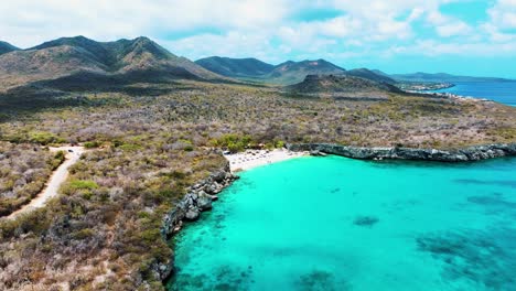 El-Dron-Vuela-Sobre-El-Océano-Mirando-Una-Pequeña-Playa-Y-Las-Montañas-Al-Fondo-En-Imágenes-Aéreas-De-Curacao-4k