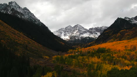 Colorful-Colorado-cinematic-aerial-drone-Aspen-Maroon-Bells-Capital-Peak-wilderness-14ers-autumn-fall-Aspen-Trees-first-snow-cloudy-morning-dramatic-incredible-landscape-circle-right-motion