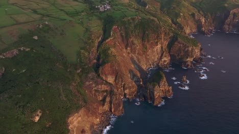 High-cliff-coastline-at-Flores-island-Azores-during-sunset,-aerial