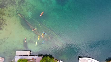 Group-of-people-paddle-boarding,-canoeing-over-shipwreck-Georgian-bay