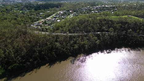 Oxenford,-Gold-Coast,-4-January-2024---Aerial-views-of-the-road-adjacent-to-the-Coomera-River-in-Oxenford-with-stripped-trees-from-the-January-storms
