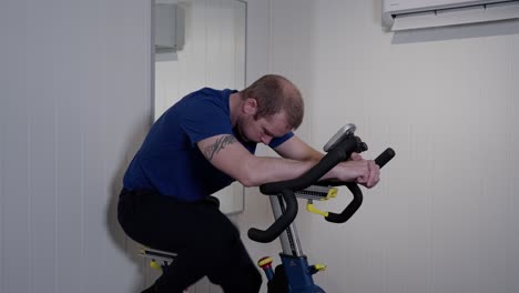 Caucasian-middle-aged-man-riding-indoor-bike-in-his-home-gym